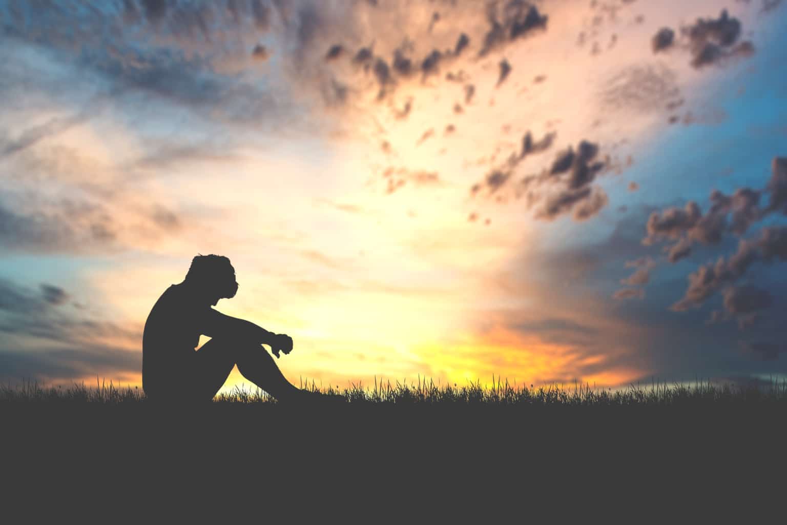 The concept of despair, discouragement, and loneliness. Silhouettes of people, sitting with their heads down in sorrow in the meadows. Online Therapy for Depression may be beneficial.